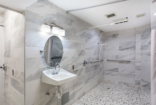 A modern accessible bathroom featuring a sink, mirror, and stylish tile design.