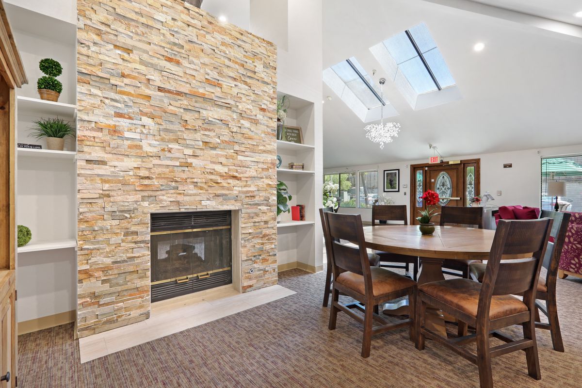 A modern living and dining area with a stone fireplace and skylights enhancing natural light.