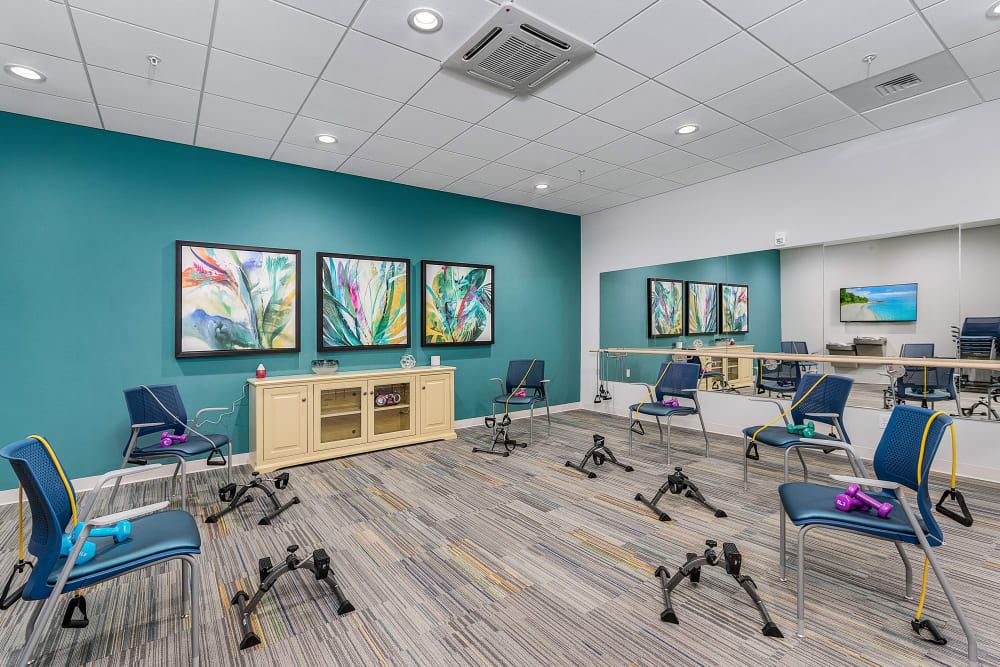 A modern exercise room equipped with chairs and colorful paintings, featuring mirrors and stylish decor.