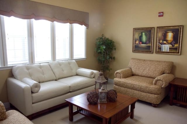 A cozy living room with two sofas, a coffee table, an indoor plant, and a painting on the wall.
