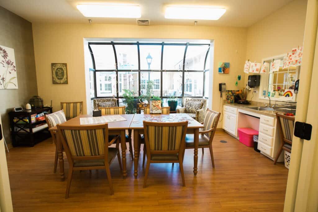 A well-lit dining area with a wooden table and matching chairs, featuring a large window that brings in natural light.