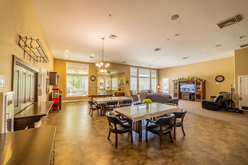 A spacious and bright common area featuring dining tables, comfortable seating, and a television.