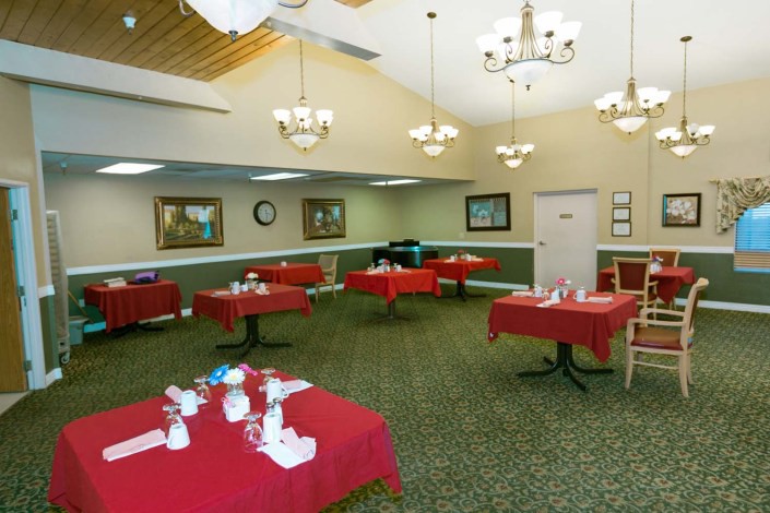 An elegant dining room with red tablecloths and chandeliers.