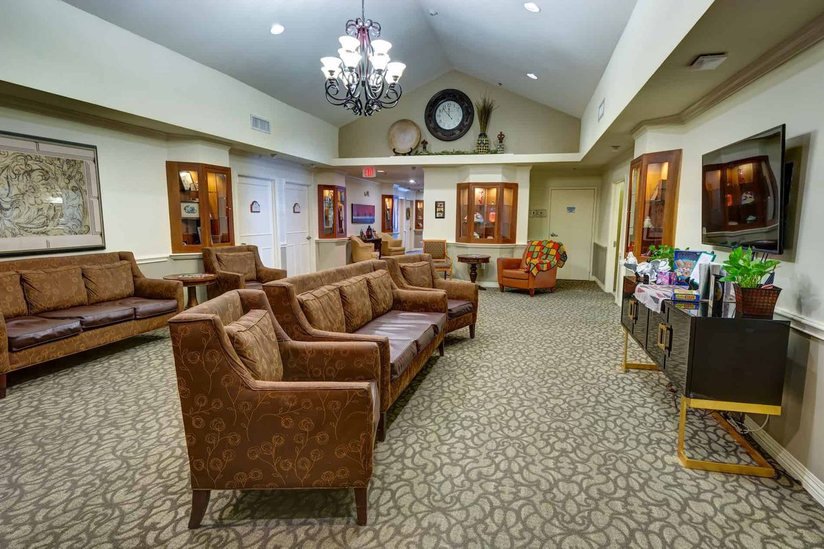 A cozy living room with brown sofas, a chandelier, and a carpeted floor.
