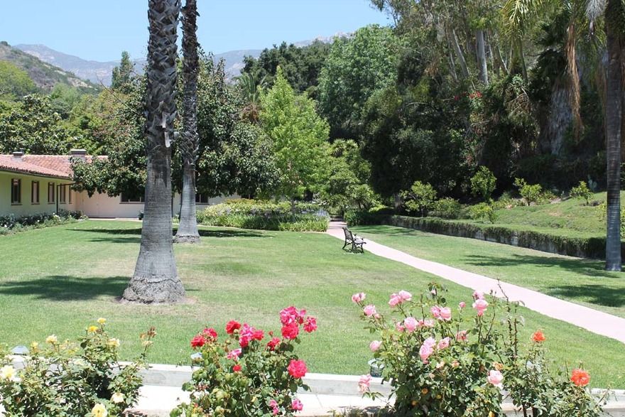 A tranquil park scene featuring a pathway surrounded by lush greenery and colorful flowers.