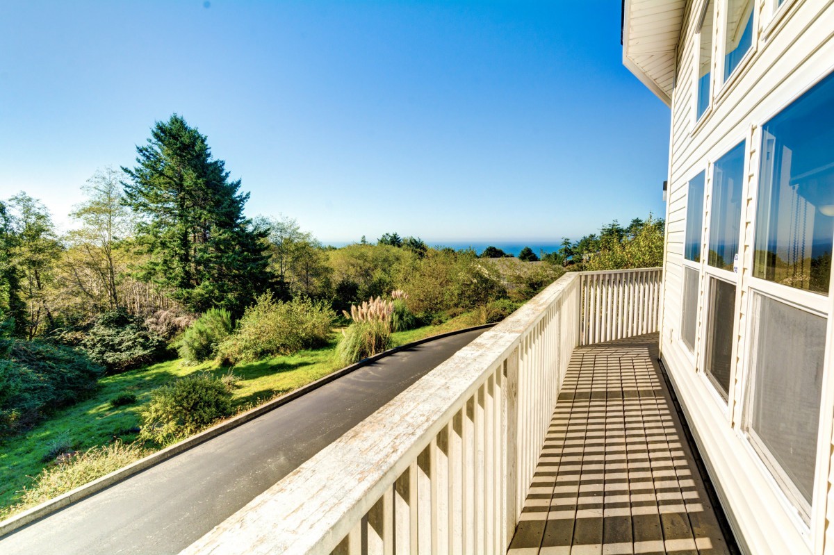 A scenic view from a balcony, overlooking lush greenery and trees under a clear blue sky.