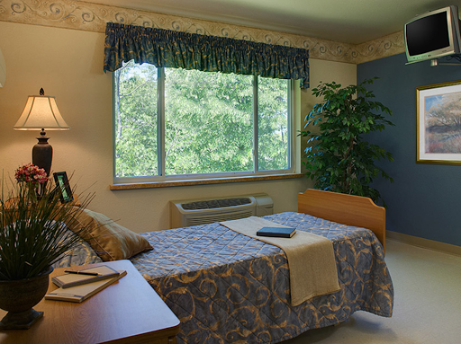 A cozy bedroom featuring a large window with a view, neatly made bed, and decorative touches.