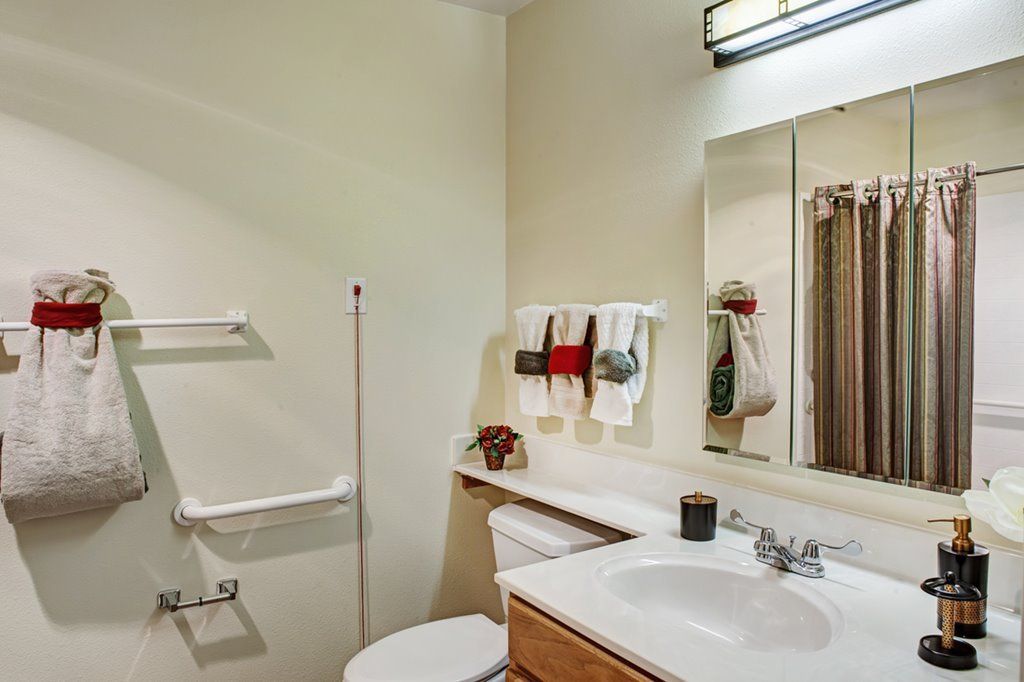 A clean and organized bathroom with a sink, mirror, and neatly hung towels.