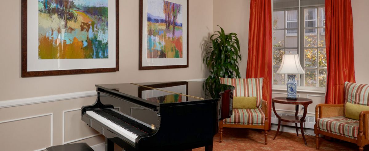A cozy living room featuring a grand piano, vibrant artwork, and comfortable seating.