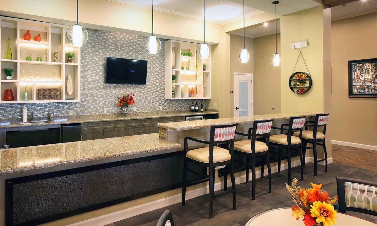 A modern bar interior with a sleek counter, high chairs, and stylish lighting.