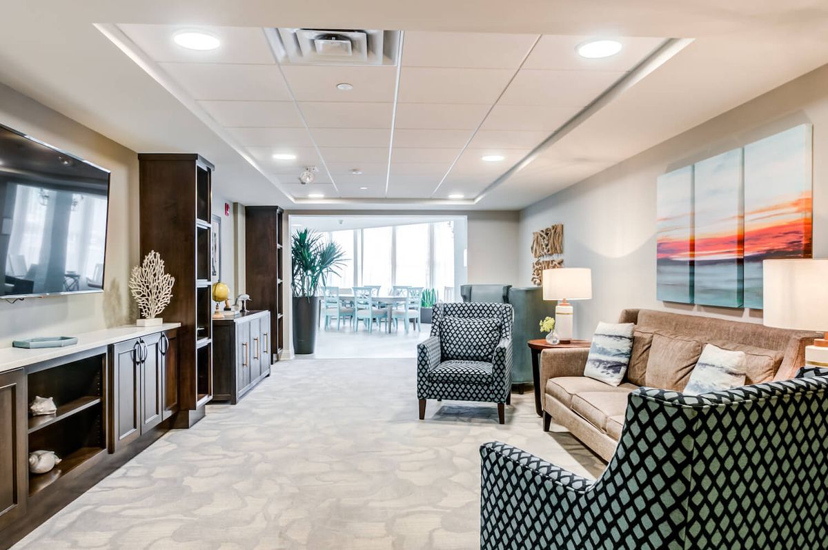 A modern and spacious living room with stylish furniture and decor, featuring a carpeted floor and ample lighting.