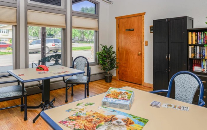 A cozy office space with desks, a plant, and puzzles on the table.