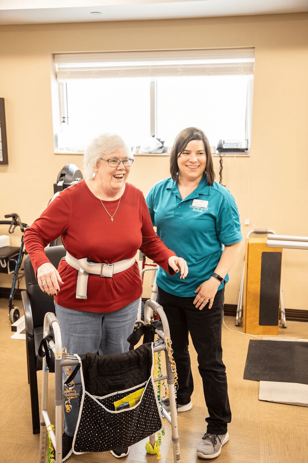 A therapist assists an elderly woman during a physical therapy session.