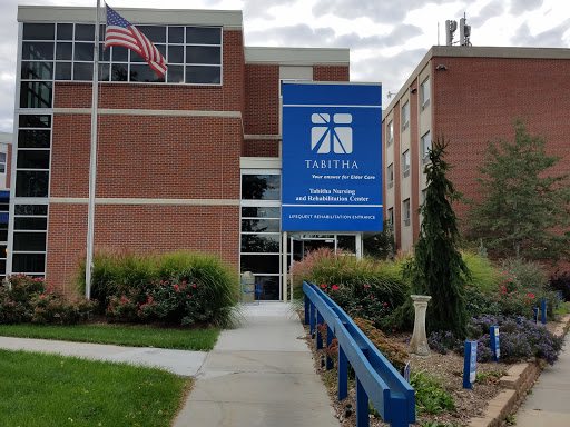 A view of a brick building featuring a large blue sign and an American flag.