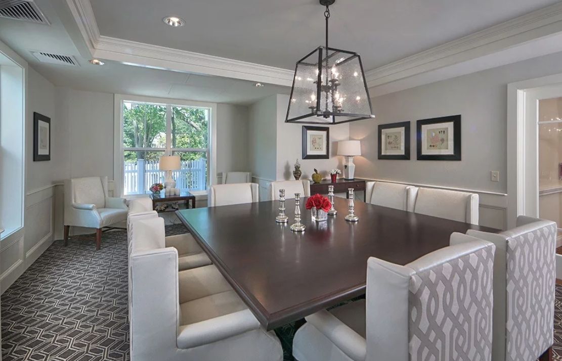 A modern dining room with a large table and elegant light fixture.