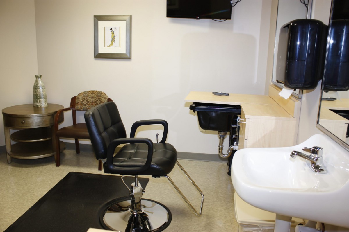 A hair salon interior with a styling chair, sink, and mirror.
