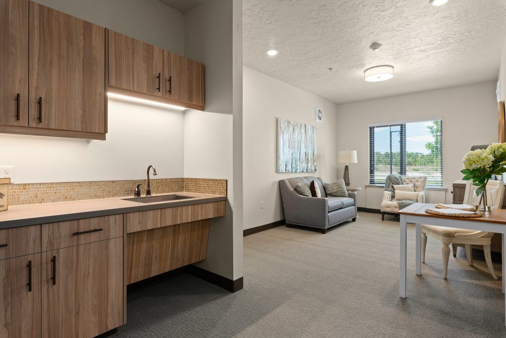 A modern apartment interior featuring a kitchenette and a cozy living room with ample natural light.