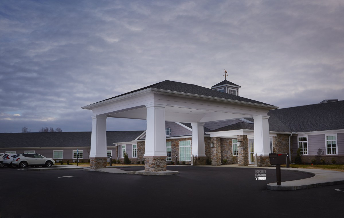 A modern building entrance with a covered driveway under a cloudy sky.