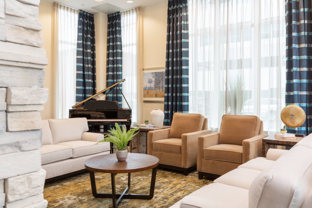 A modern living room featuring comfortable sofas and armchairs, a piano in the corner, and elegant decor.
