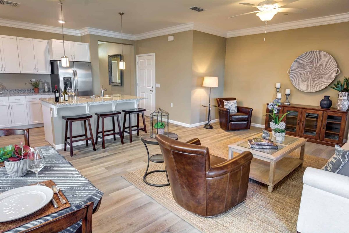 A modern open-concept living room with a connected kitchen, featuring stylish furniture and hardwood floors.