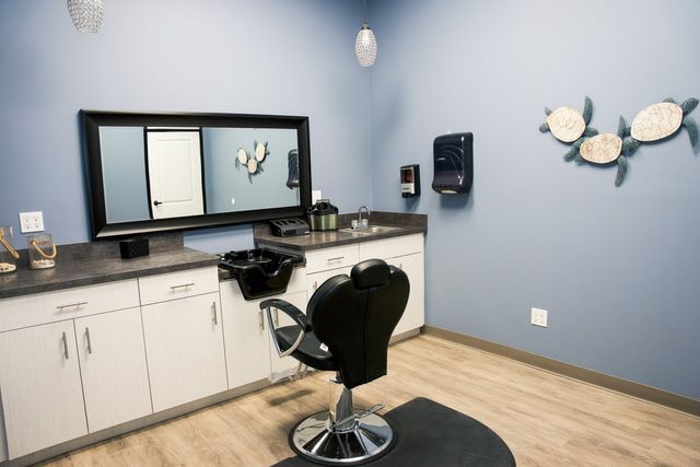A modern hair salon station with a barber chair and mirror.