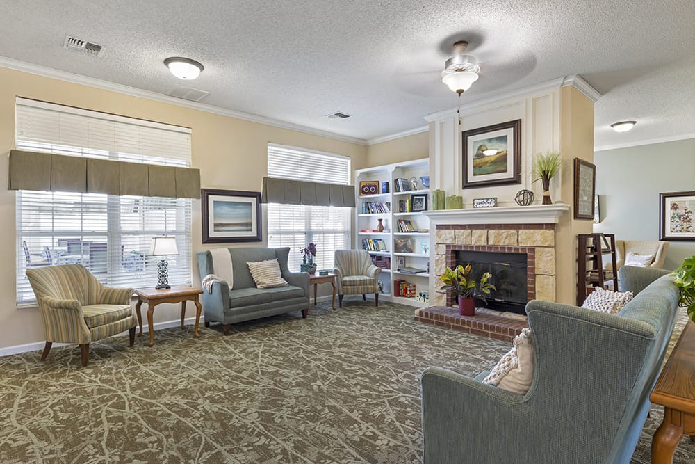 Cozy living room with a fireplace, armchairs, and bookshelves.