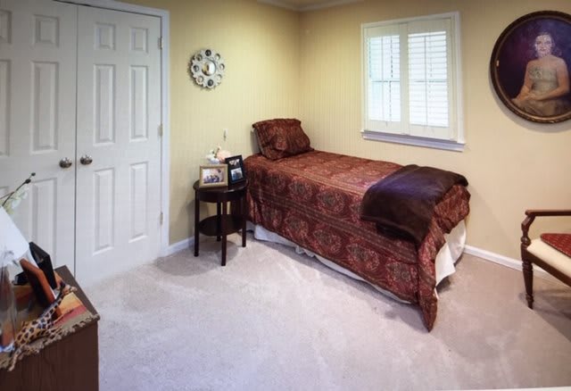 A cozy bedroom with a single bed, nightstand, and clock on the wall.