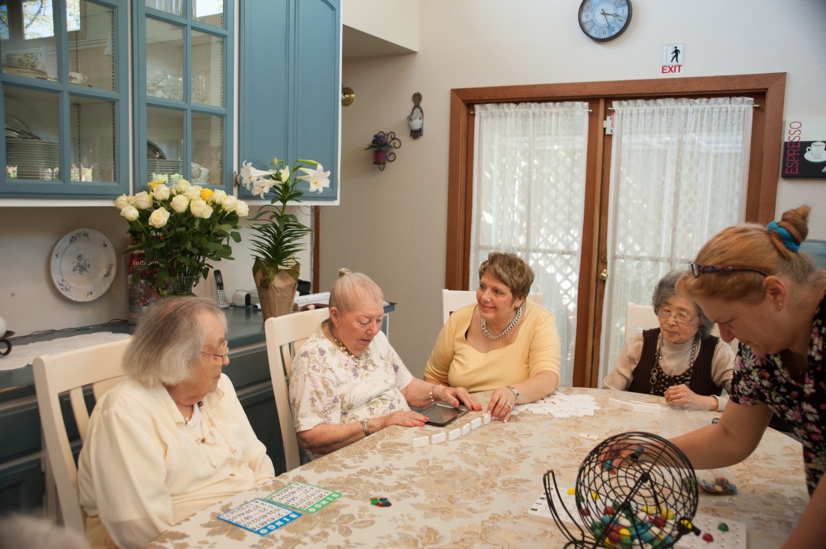 A group of elderly women sitting around a table, engaged in conversation.