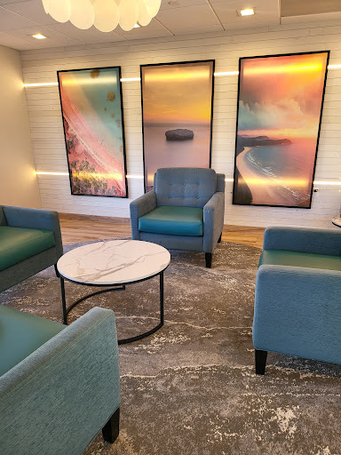A cozy lounge area featuring teal chairs, a marble table, and vibrant artwork.