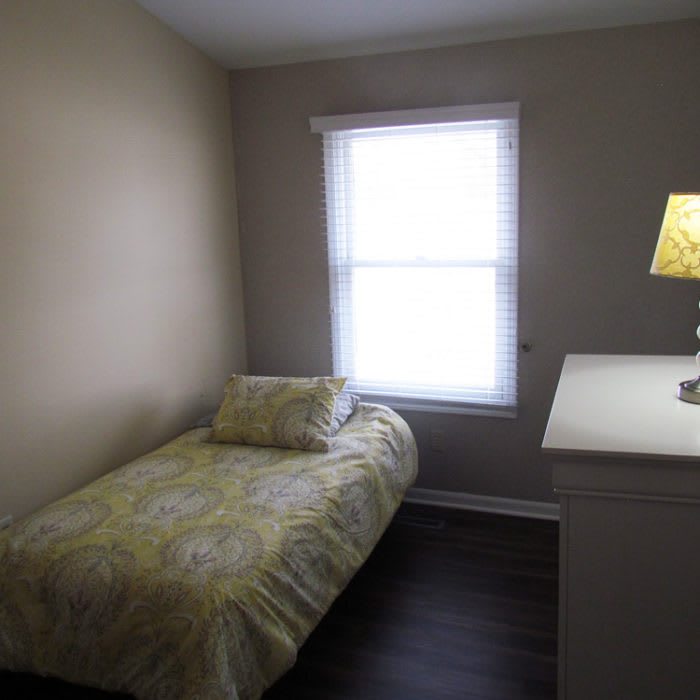 A small, minimalist bedroom with a single bed and dresser.
