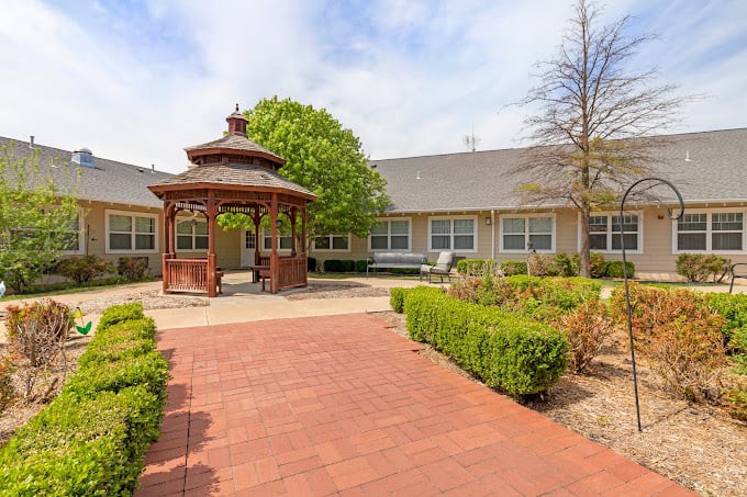 A serene courtyard featuring a gazebo surrounded by well-maintained bushes and a paved walkway.