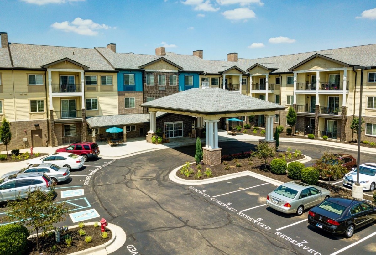 A modern apartment complex with a landscaped entrance and parking lot.