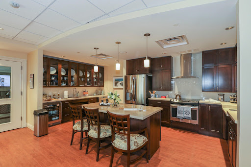 A modern kitchen featuring dark wood cabinets, stainless steel appliances, and a cozy dining area.