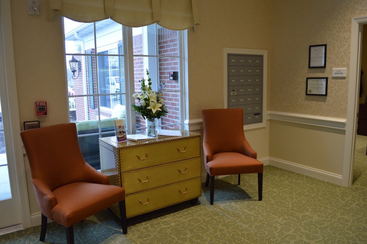 A cozy corner with two chairs and a dresser near a window.