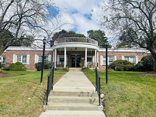 An inviting entrance to a well-maintained building surrounded by greenery and a clear blue sky.