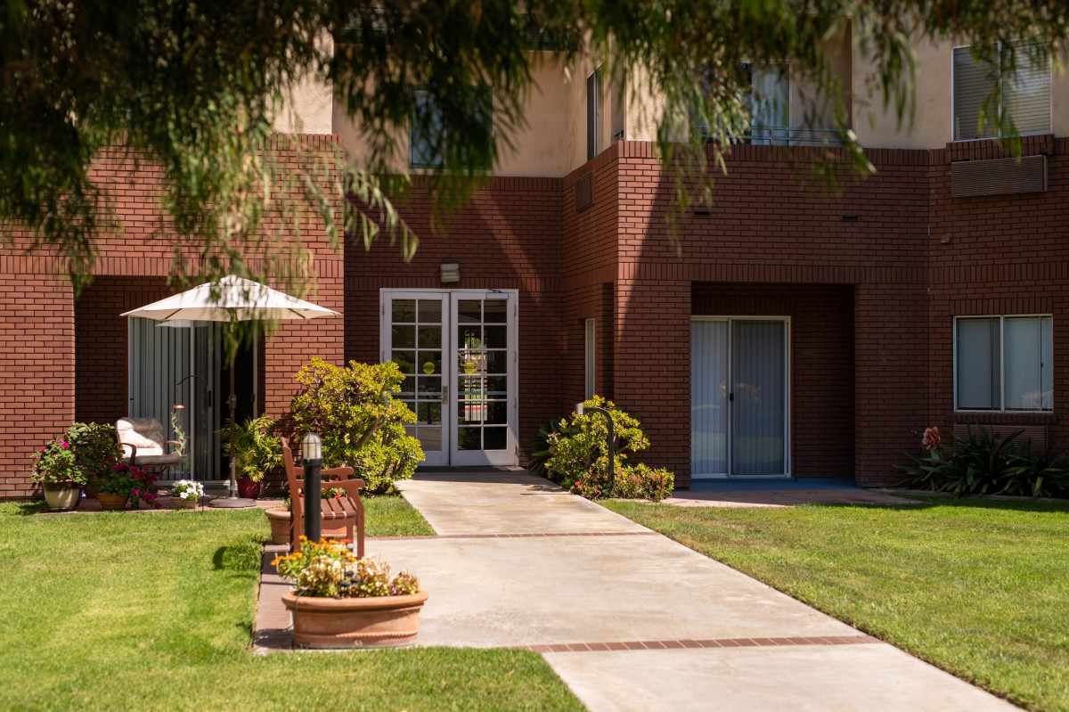 A well-maintained residential entrance with a lawn and patio area.
