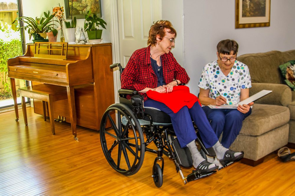 A caregiver assists an elderly person in a wheelchair indoors, emphasizing healthcare and support.