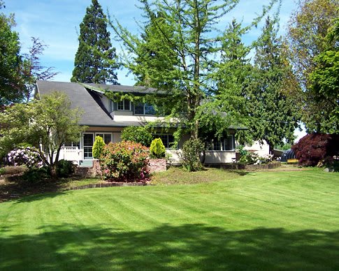 A beautiful residential house surrounded by a lush garden and well-maintained lawn.