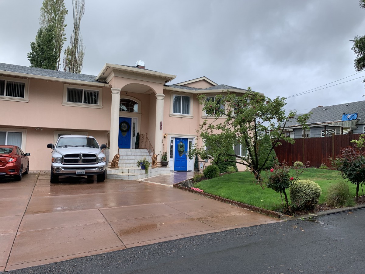 A suburban house with a driveway and car on a cloudy day.
