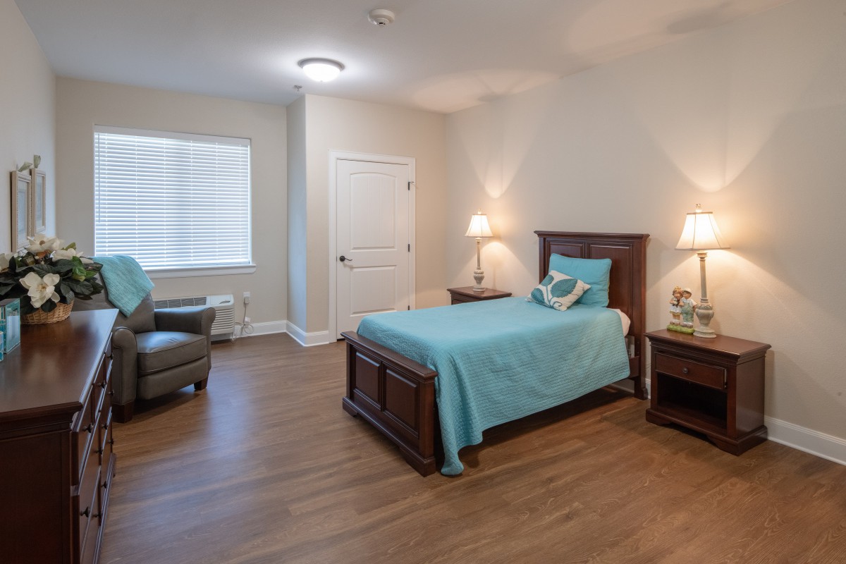A cozy bedroom with a single bed, wooden floor, and soft lighting.