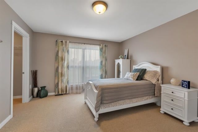 A cozy bedroom with a neatly made bed, curtains, and warm decor.