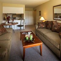 A cozy living room with a sofa and coffee table, adjacent to a small dining area.