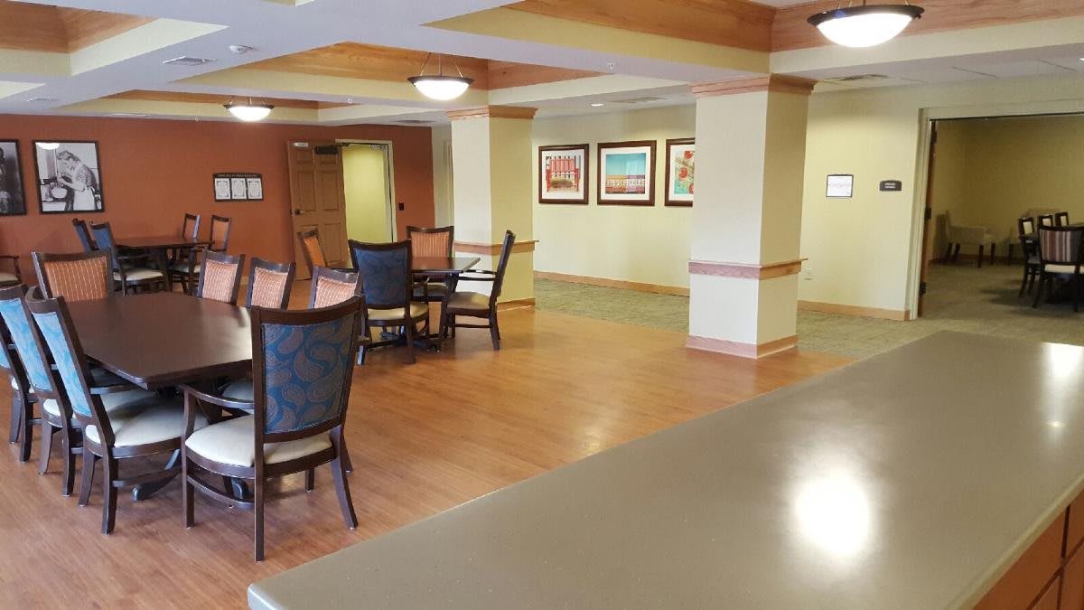 A spacious dining area with chairs and tables, featuring artwork on the walls and wooden flooring.