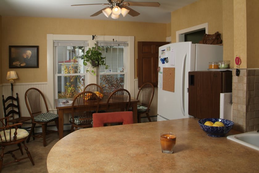 A cozy kitchen with a dining table, chairs, and a plant near the window.