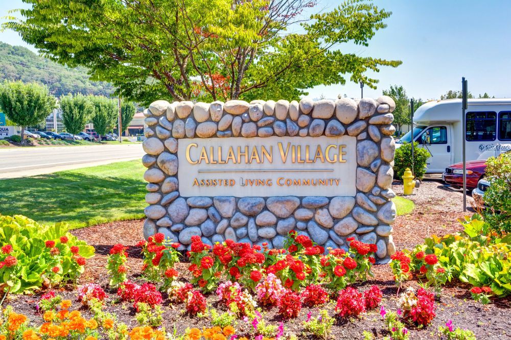 A stone sign surrounded by colorful flowers and greenery in a landscaped garden.