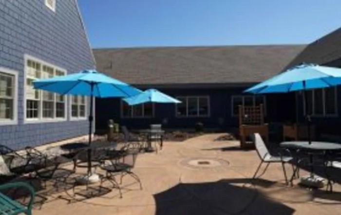 A sunny patio with blue umbrellas and seating arrangements.