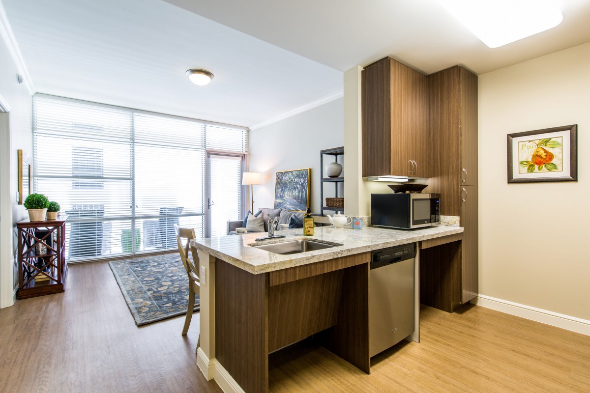 A modern open-plan kitchen and living area in an apartment, featuring sleek appliances and stylish decor.