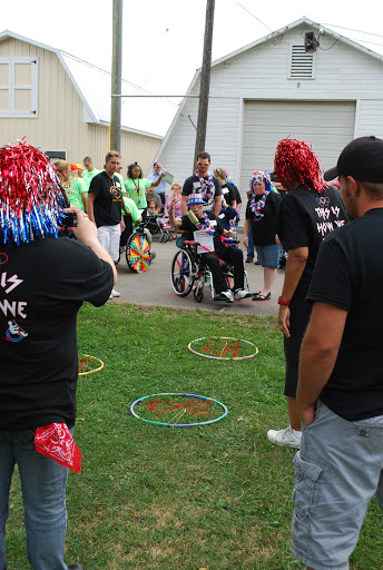 A lively community event featuring participants engaged in various activities, including a person in a wheelchair surrounded by supporters.