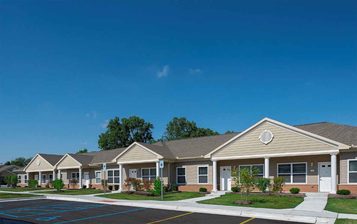 A row of suburban residential homes under a clear blue sky.