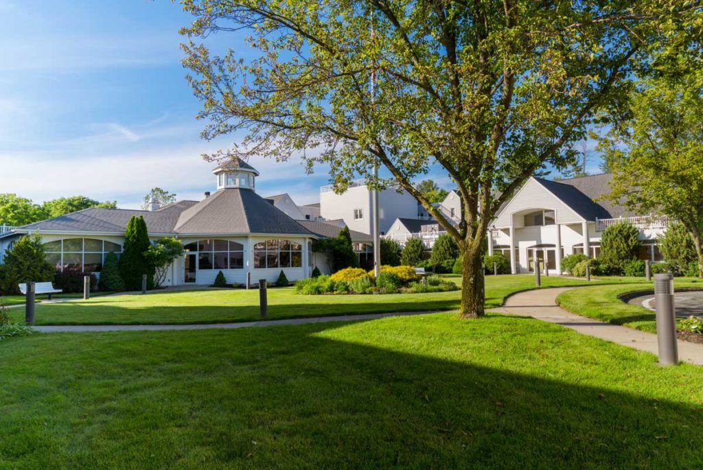 A picturesque view of a building surrounded by a lush green lawn and trees on a sunny day.